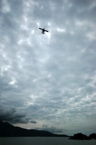 A plane flies below the cloudy sky of BC's Sunshine Coast, Canada