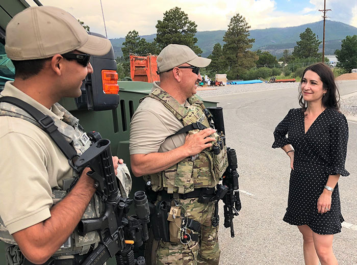 Two LANL guards talk to a woman; in the background are the Pajarito Mountains.