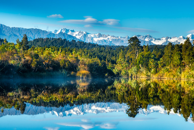 Mirror image reflections of the snow capped Southern Alps on Okarito Lagoon on the West Coast