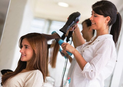 Stylist drying hair of a female client at the beauty salon
