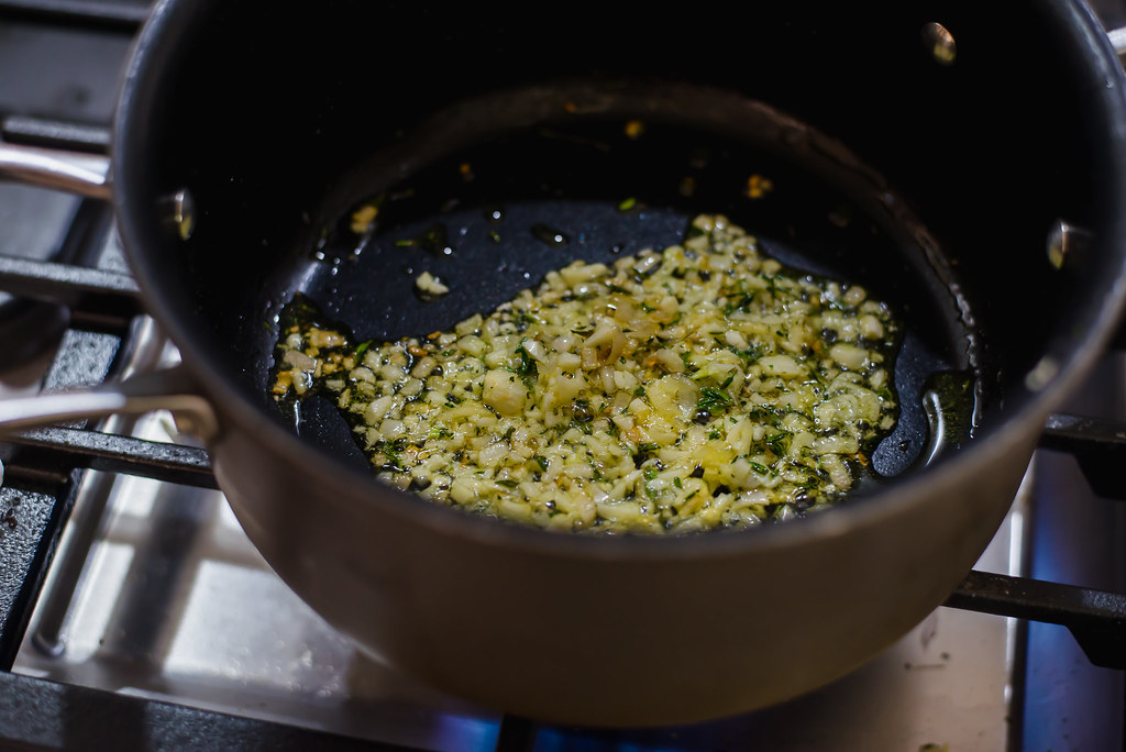 To make creamy parmesan polenta with thyme, start by sauteing shallots, garlic and thyme in olive oil.