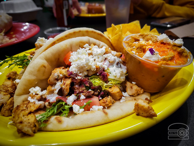 Toasted pitas loaded with sweet and savory couscous, fresh frisee, lemon-Dijon chicken, three-olive tapenade, dill tzatziki, roma tomatoes, feta cheese, and a side of red pepper hummus - Black Bear Burritos