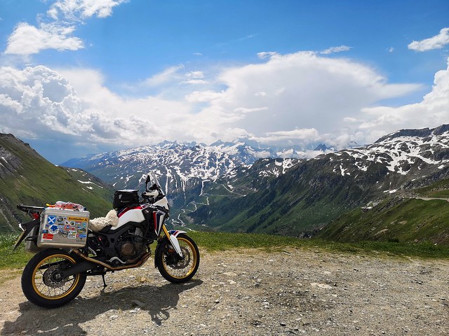 Africa Twin on the Furka pass with the Grimsel pass in the background.