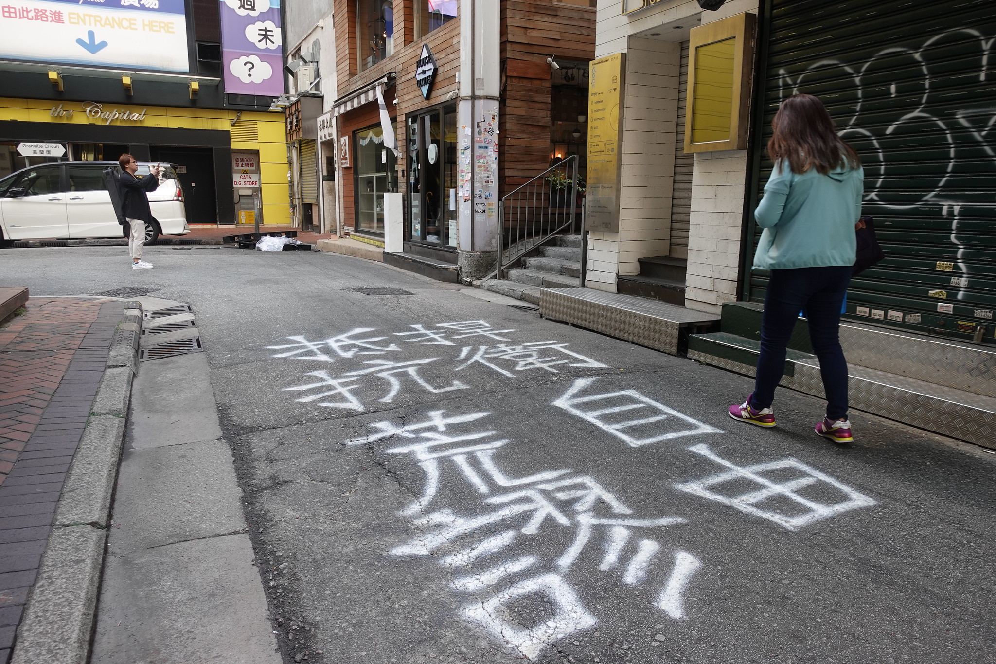 行人經過地上寫著「捍衛自由，抵抗荒謬」的塗鴉。（攝影：張智琦）