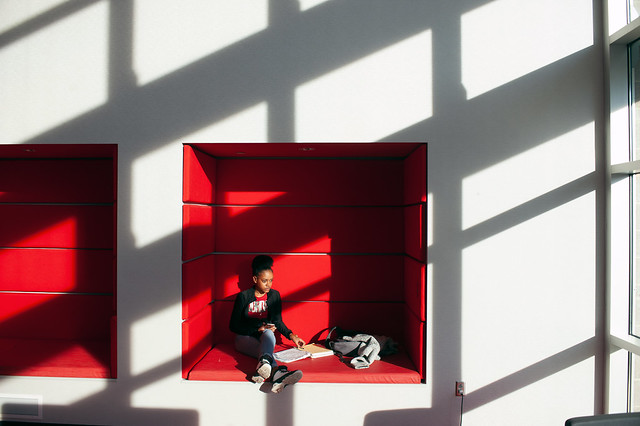 Student sitting in red wall inset in Student Success Center