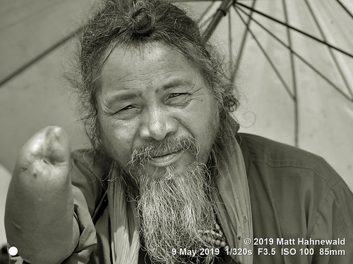 matthahnewaldphotography facingtheworld qualityphoto character head face eyes expression beard topbun parasol umbrella right hand consensual respect conceptual diversity humanity living travel society impact begging beggar local traditional cultural hindu hinduism temple roadside manakamana gorkhadistrict nepal asia asian nepali human person one male elderly man backdrop primelens nikond610 nikkorafs85mmf18g 85mm street portrait closeup headshot fullfaceview outdoor blackandwhite monochrome greyscale bandicoot vignette photoscape editing posing authentic serious amputee clarity poor poverty lookingatcamera