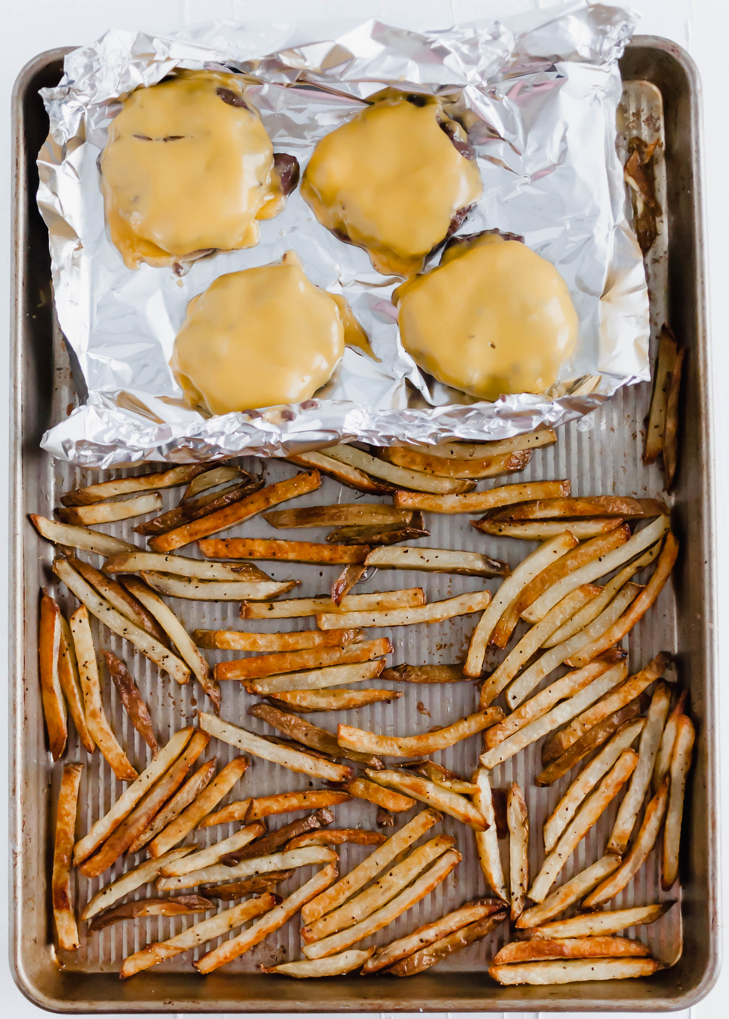 You don't need warm weather to enjoy a burger at home. These Sheet Pan Burgers and Fries are super simple to make all on one pan. A great, simple weeknight meal.