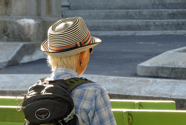 Sitting woman wearing hat, sunglasses, and backpack Music Concourse in San Francisco's Golden Gate Park 20191020-132550 cw50 C4