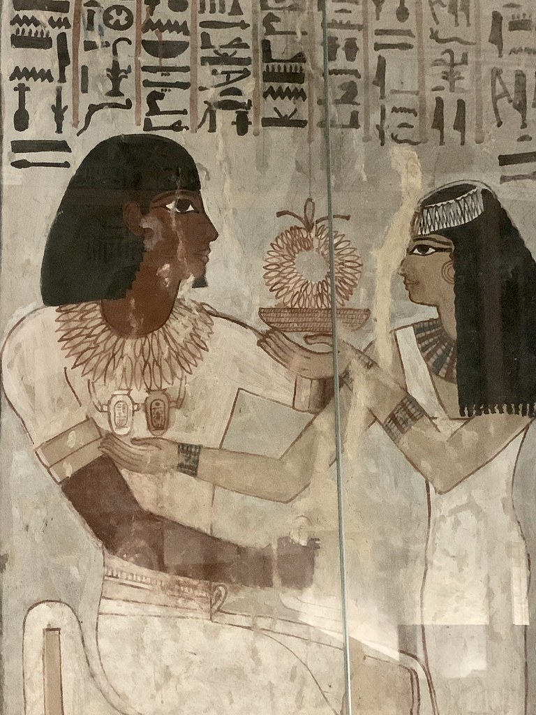Tomb of Sennefer, Burial Chamber, NorthWest Pillar, South Face : Meryt presents a gold necklace on a golden dish to Sennefer, and extends her right hand towards the double heart amulet that bears the name of King Amenhotep II