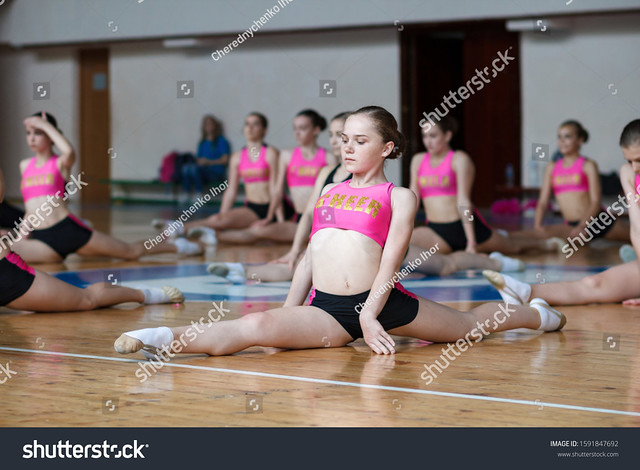 sport young woman in black and pink sportswear sitting on the floor, horizontal twine, dancer practicing stretching, girl cheerleader doing acrobatic and flexible tricks, fitness, stretching workout