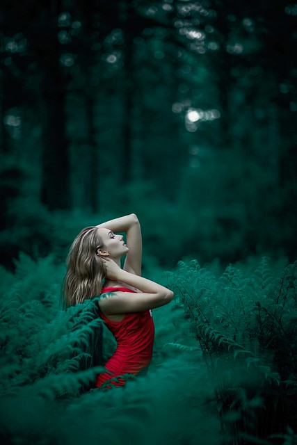 Woman wearing red sleeveless dress standing near fern leaves - Credit to https://homegets.com/