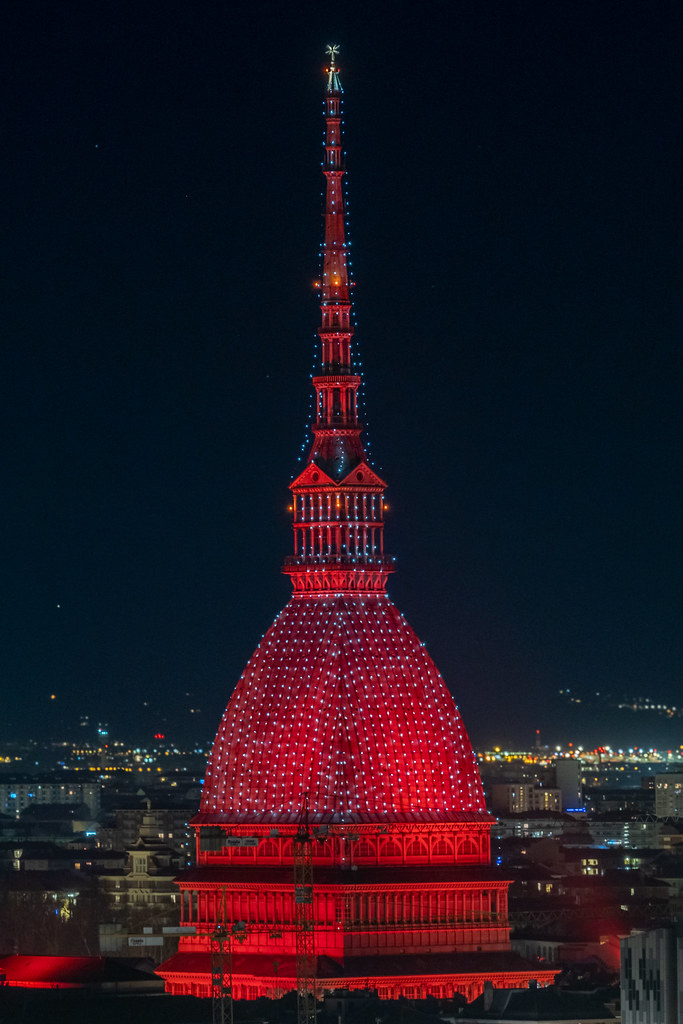 Scenic night cityscape of the Mole Antonelliana  inTurin lighted in red , Italy
