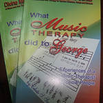 The image shows two Music Therapy books. The background shows color green, yellow green, dark green, blue, a little violet and red with a song paper with a title "O Divine Mercy".