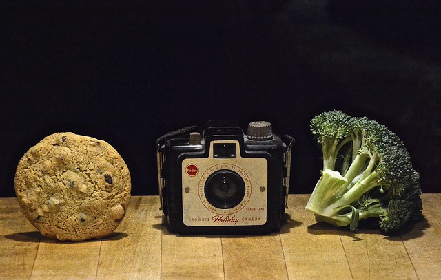 A Brownie Holiday Camera Caught Between a Chocolate Chip Cookie and Broccoli (a still life)
