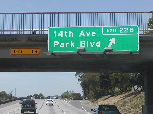 Interstate 580 Westbound General Douglas MacArthur Freeway approaches at Exit 22B - 14th Avenue and Park Blvd. (Cross-Traffic Intersection Traffic Signal Lights Ahead at this Exit Off-Ramp) followed by Exit 22A - Lakeshore Avenue