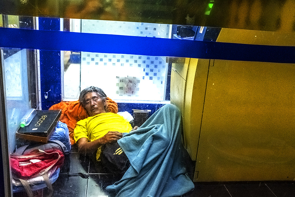 Man sleeping inside ATM booth--Vientiane