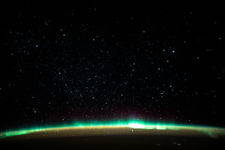 An aurora blankets the Earth beneath a celestial night sky | by NASA Johnson
