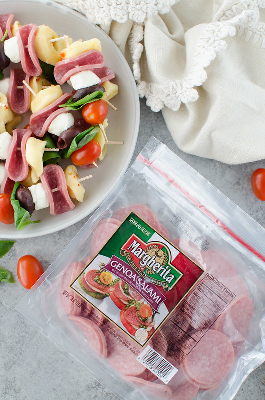 Antipasto Skewers - the easiest party appetizer! Cheese tortellini, Genoa salami, mozzarella balls, fresh basil, olives, and grape tomatoes layered on skewers. 