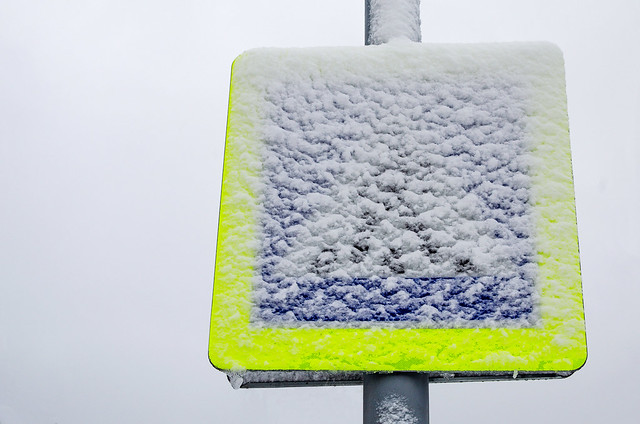 Pedestrian crossing road sign in the snow. After the snowfall on the street