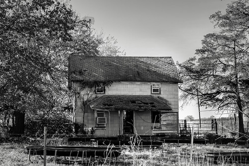 abandonedhouse shadows opendoorway monochrome grass brokenroof trees pasture antenna fence junk blackandwhite faded brokenwalls weathered