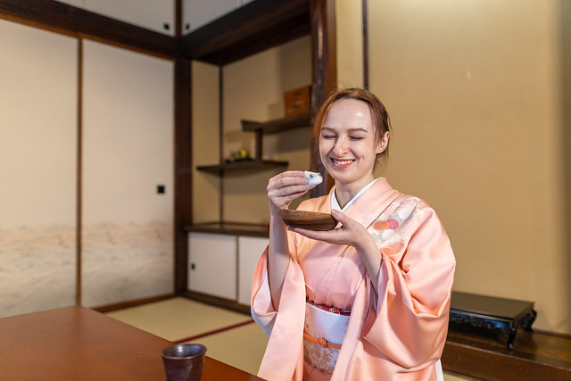 Russian woman in kimono smiling with eating Japanese wagashi sweets