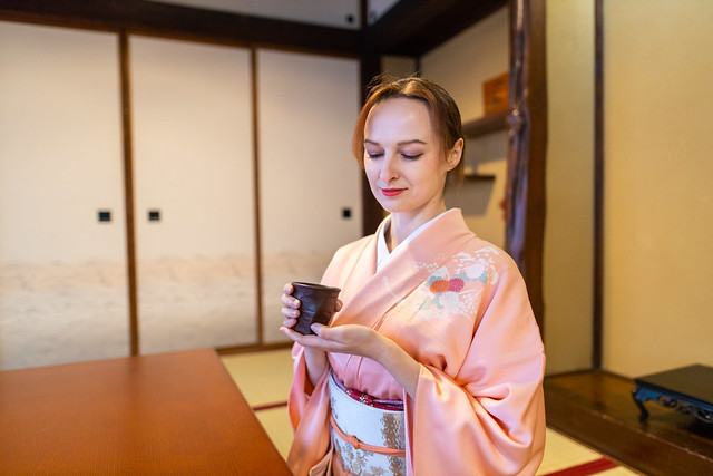 Russian woman in kimono resting in tatami room with Japanese tea and wagashi sweets