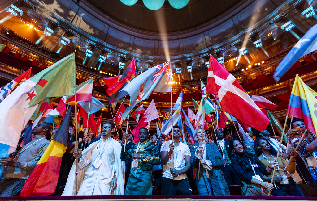 A group of people waving world flags in the air at the One Young World 2019 event 