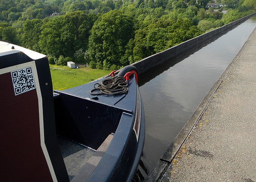 Canal boat making its way down the narrow canal on top of the Pontcysylite Aqueduct in Wales