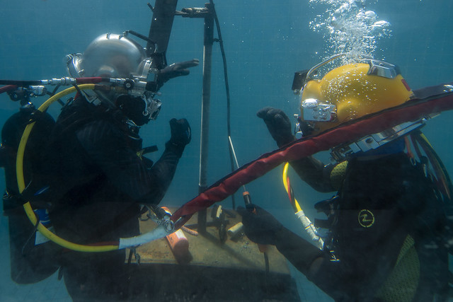 Navy Sailor and Royal Thai navy work together to set up the underwater station in the dive training pool for Exercise Cobra Gold 2020