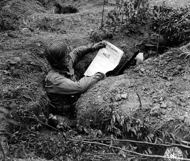 SC 190598 - In the shelter of their foxhole, two GIs read the latest issue of 