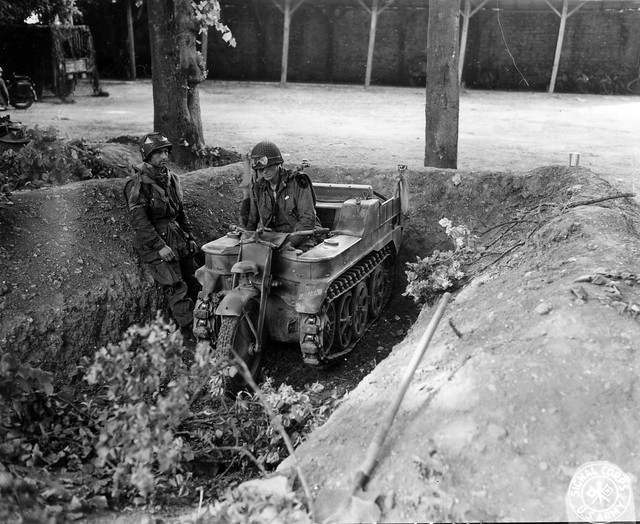 SC 190596 - Members of an American Airborne repair German vehicles for their own transportation. Here experimenting with a German tracked motorcycle.