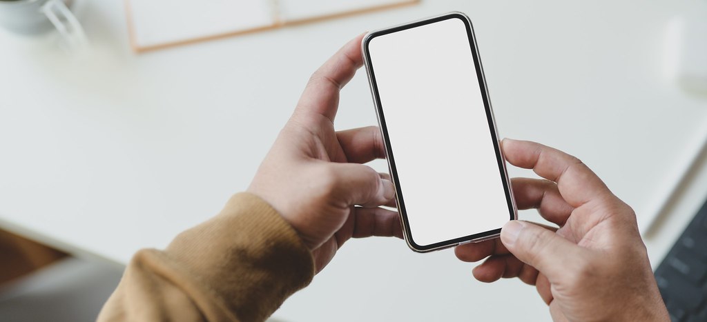 Person in brown sweater holding cellular - Credit to https://homegets.com/