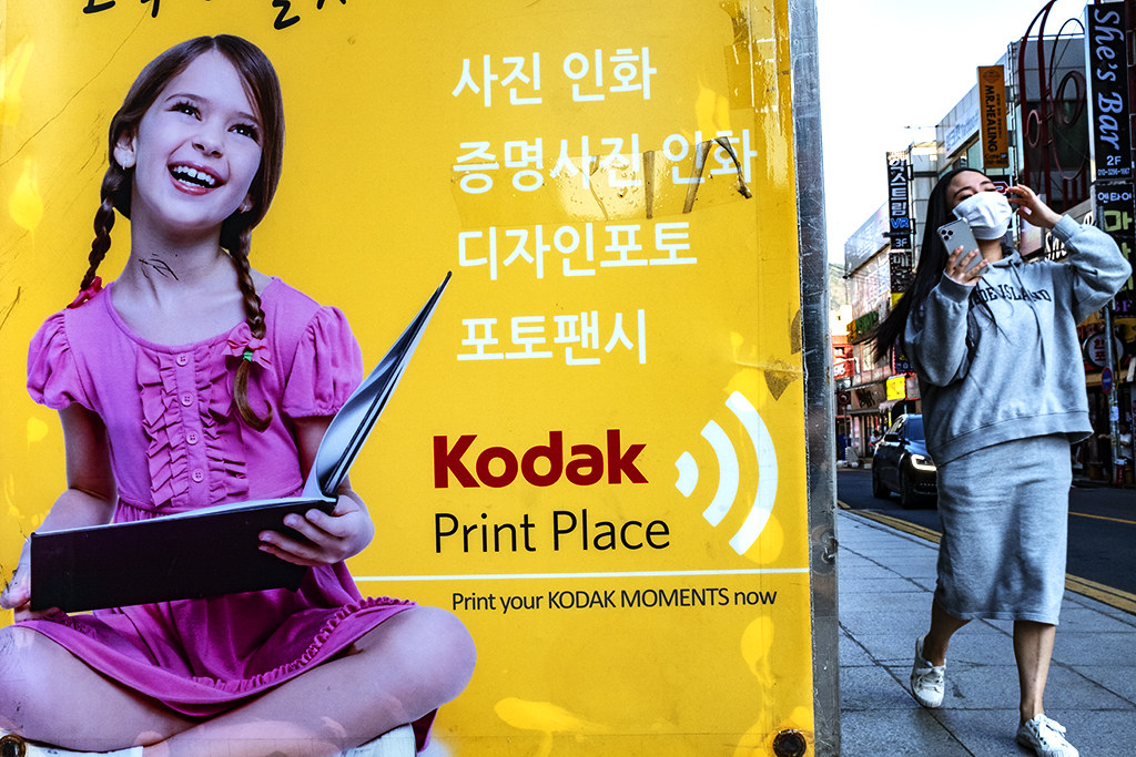 White girl on Kodak Print Place sign and young woman walking by--Changwon