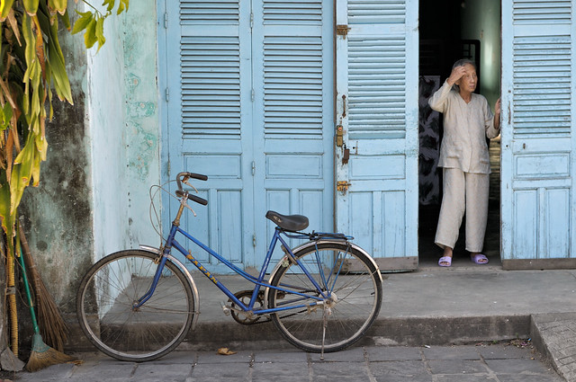 Old woman in front of her blue shutters door in Hoi An - Vietnam