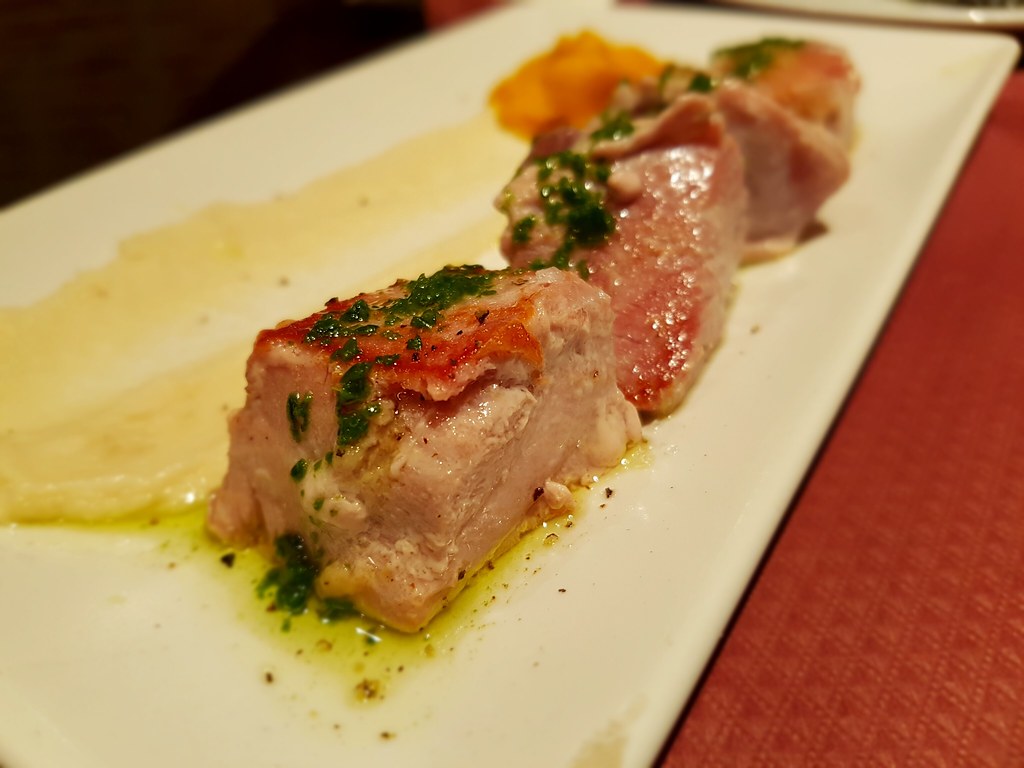 A plate of seared tuna with a yellow sauce