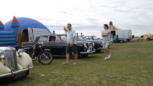 MEN WALKING PAST RETIRED  WOLSELEY POLICE CAR AT DAMYNS HALL AERODROME CAR AND MILITARY SHOW IN AN EAST LONDON BOROUGH SUBURB STREET PARK VENUE EVENT ESSEX ENGLAND SS854378 9-8-2015