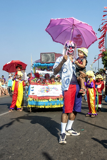 The Clown with a Pink Umbrella in one Hand and a Baby in the Other. Carnival Goa