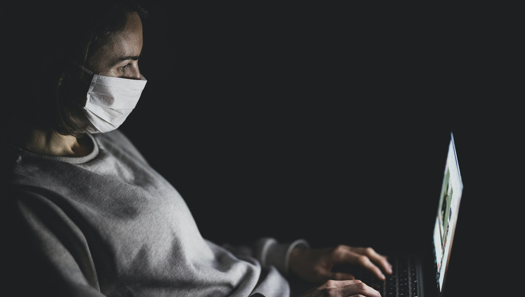 Woman works on laptop wearing a face mask
