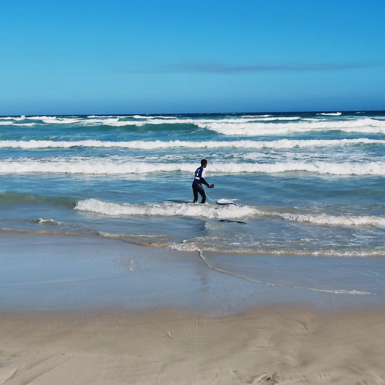 Young surfer going into the water at Muizenberg Beach