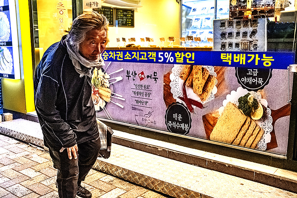 Old woman walking by fishcake store in Choryang-dong on 5-7-20--Busan