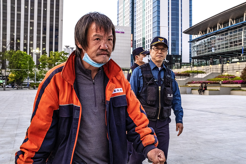 Homeless man and cops outside train station on 5-12-20--Busan