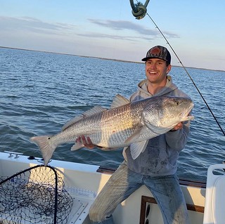 Photo of man holding a 47-inch red drum he caught and released.
