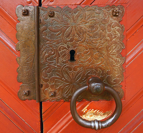 Decorative brass hinge with lock and door pull on door in the Old Village in Aarhus, Denmark