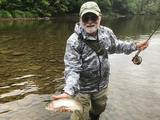 Photo of man holding a rainbow trout. 