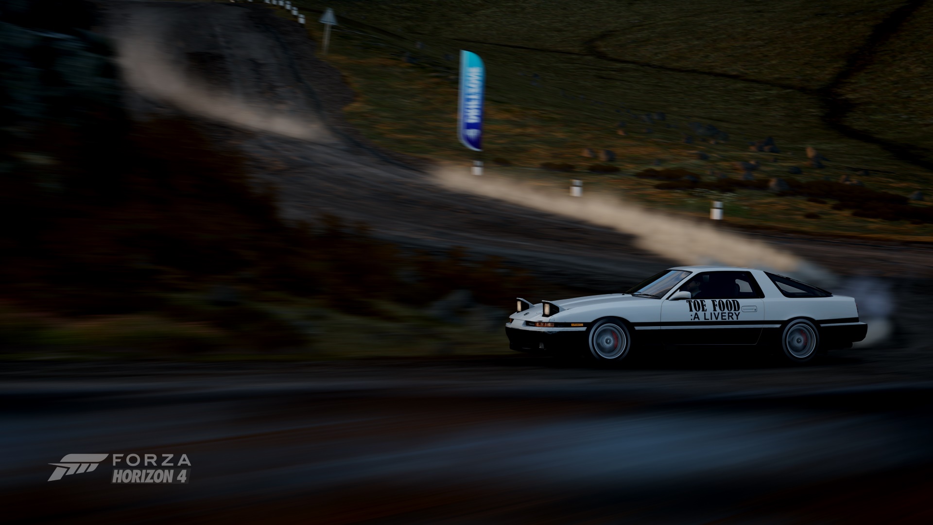 1992 Toyota Supra painted in the patern of a white AE86 with the text "Toe Food: A Livery" on the side