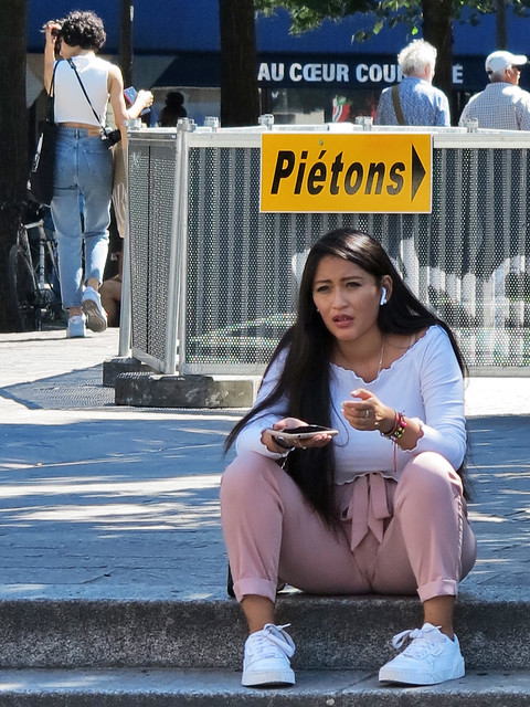 Girl in pink pants talking on the phone sitting on the ground