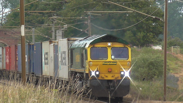 66 572 hauls a container train at speed through Baylham.