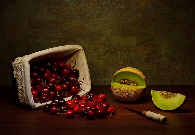 An overturned basket of cherries and melon