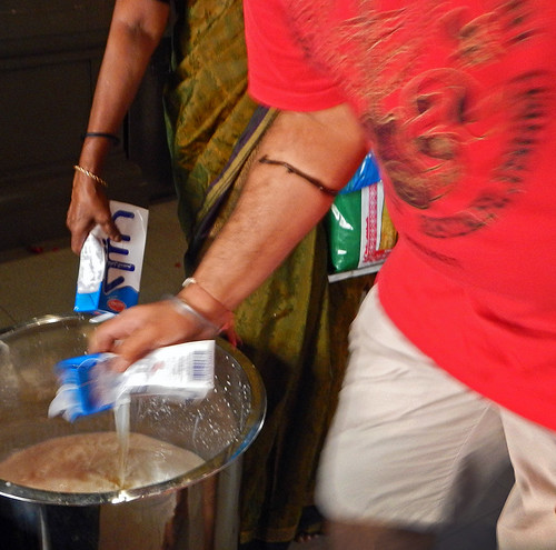 Pouring milk into a container, part of the worship at a Hindu temple in Singapore's Little India
