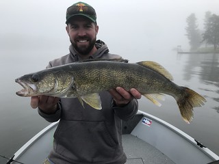 Photo of man in a small boat holding a walleye